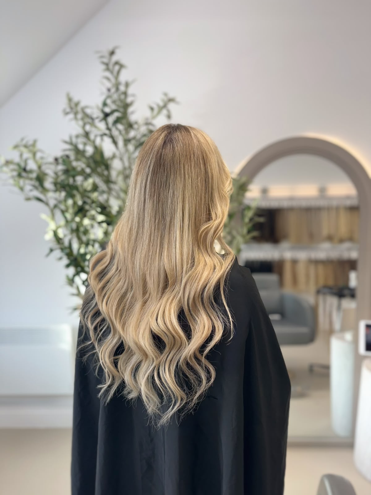 Blonde balayage extensions photographed in the studio, showing lighter ends blended down from a deeper root