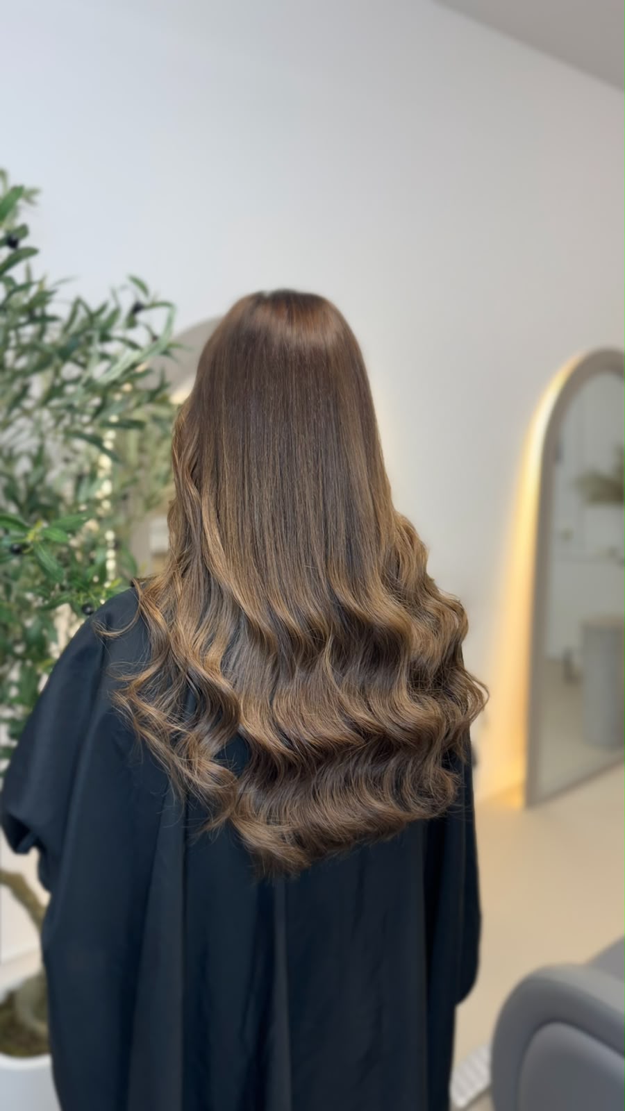 Back view of dark brunette extensions with a high-gloss finish, falling in one clean length
