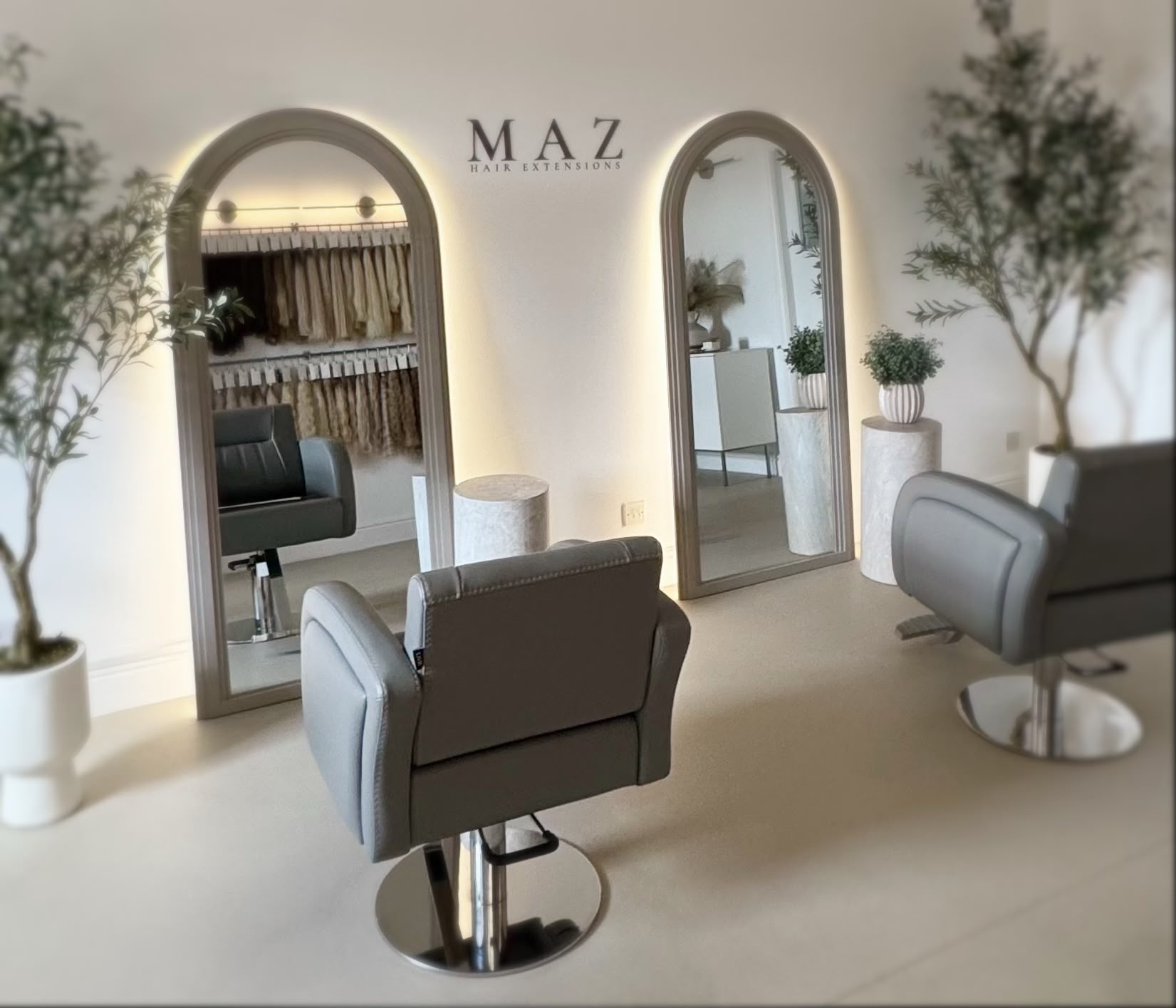 Inside the MAZ studio: a row of arched mirrors backlit with warm gold light above a pale styling counter